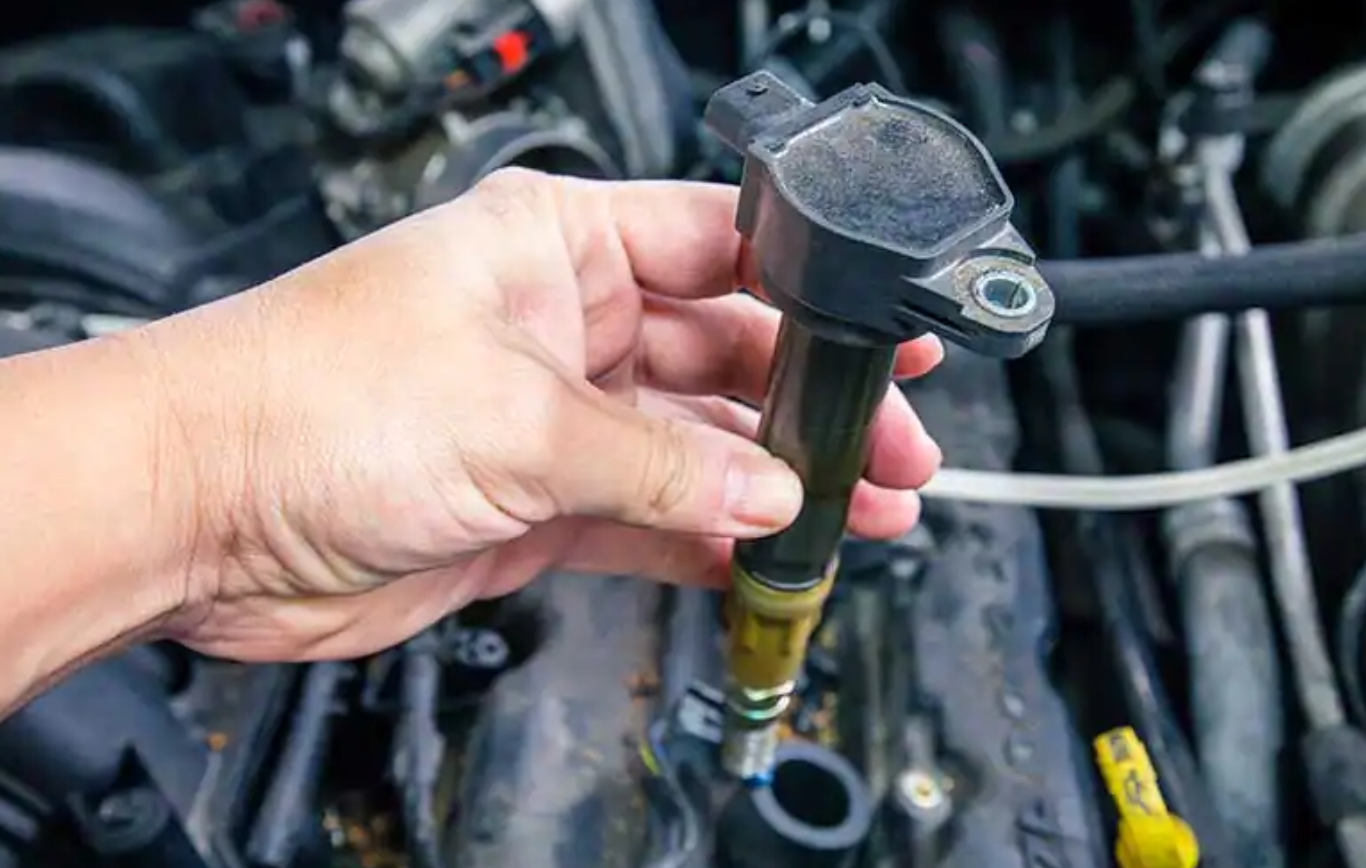 Car technician performing ignition coil replacement on engine