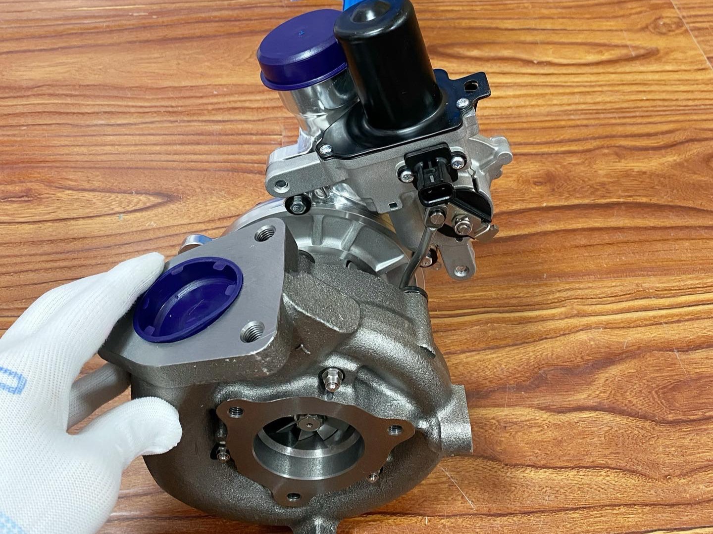 turbocharger assembly with gloved hand, showcasing precision eng