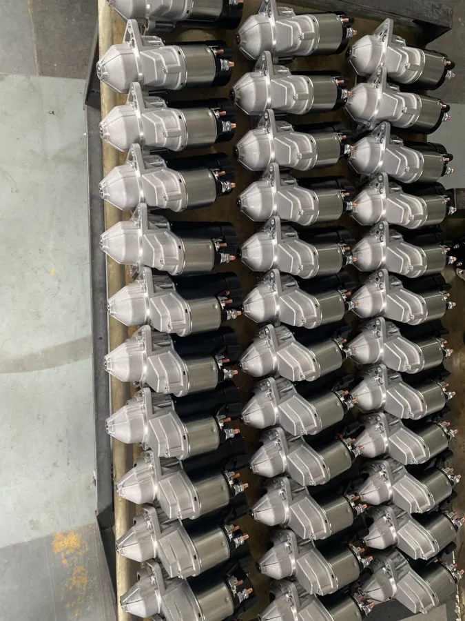 Starter assemblies arranged in rows with silver housings and black motor bodies