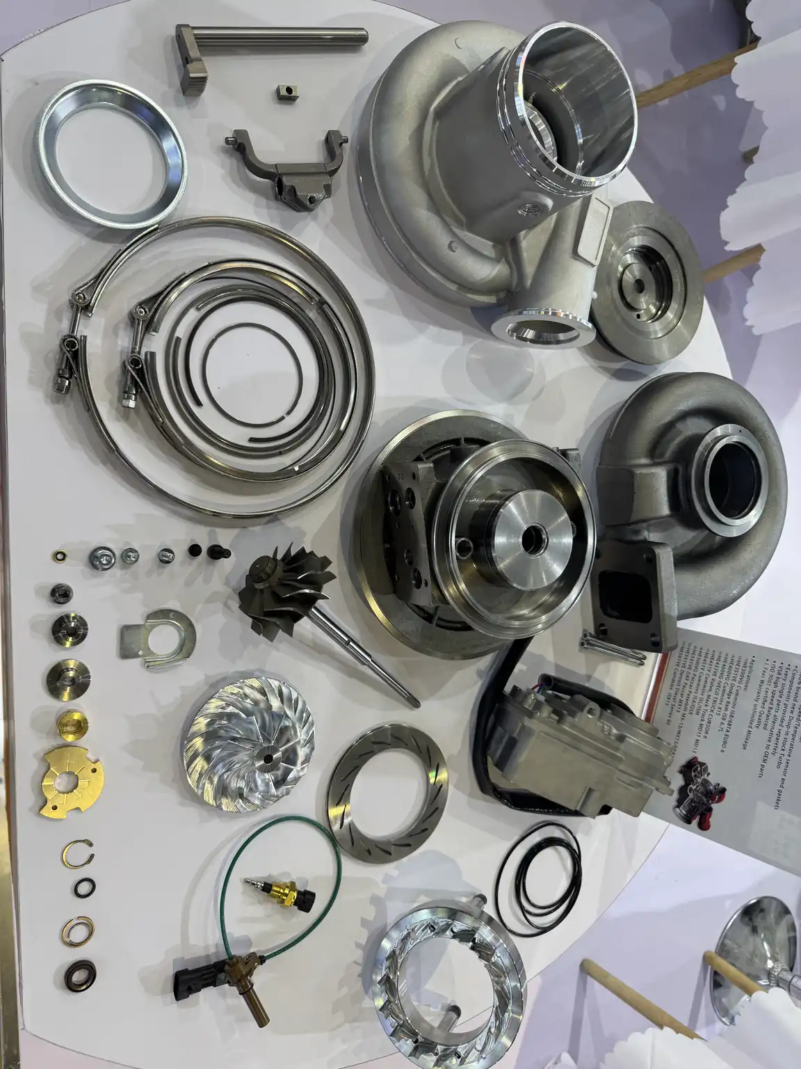 Turbocharger housings, rotating components, clamps and other parts displayed separately on a table.