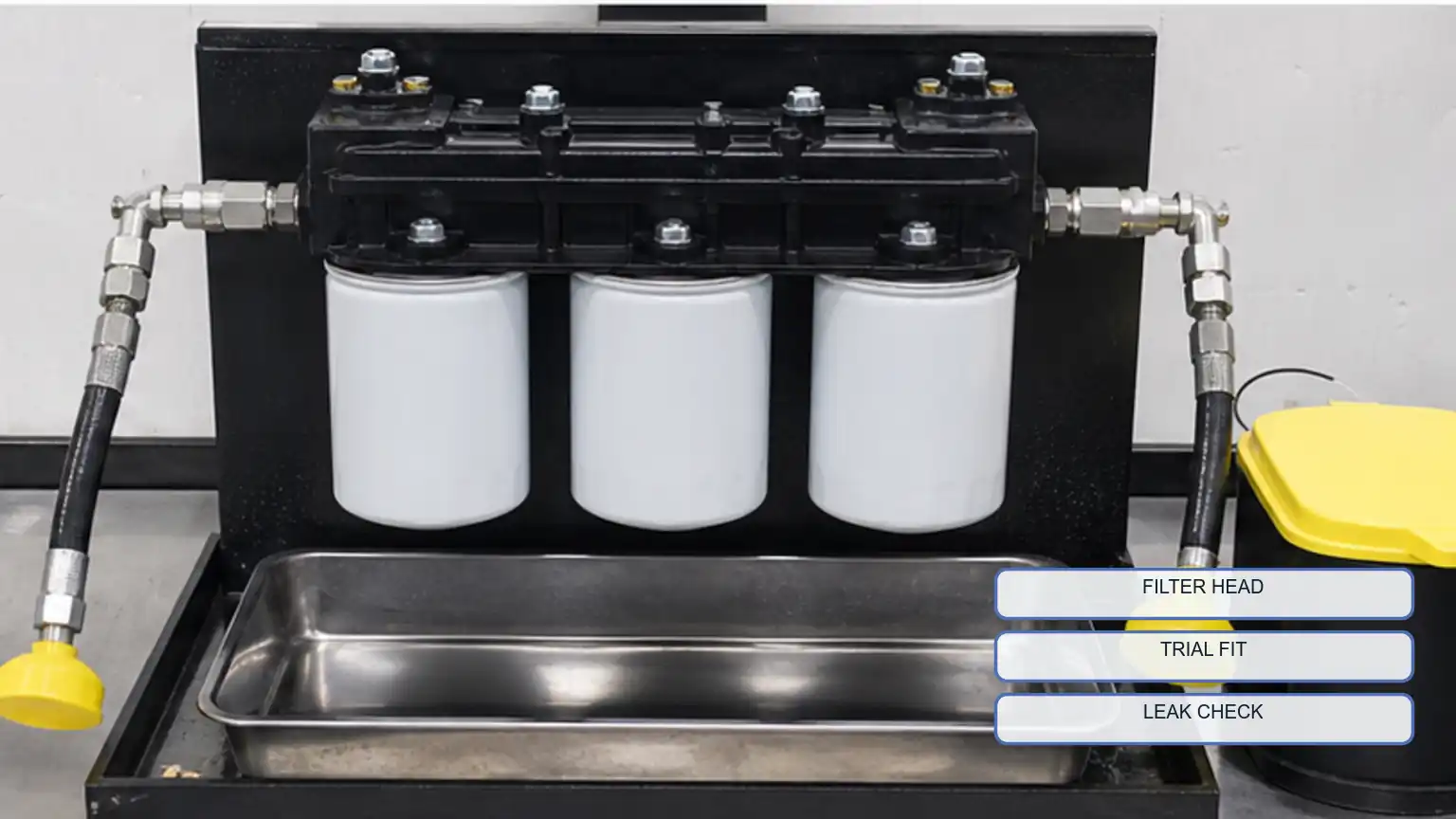 Candidate diesel fuel filters trial-fitted on a clean filter-head fixture with capped lines and a catch tray.