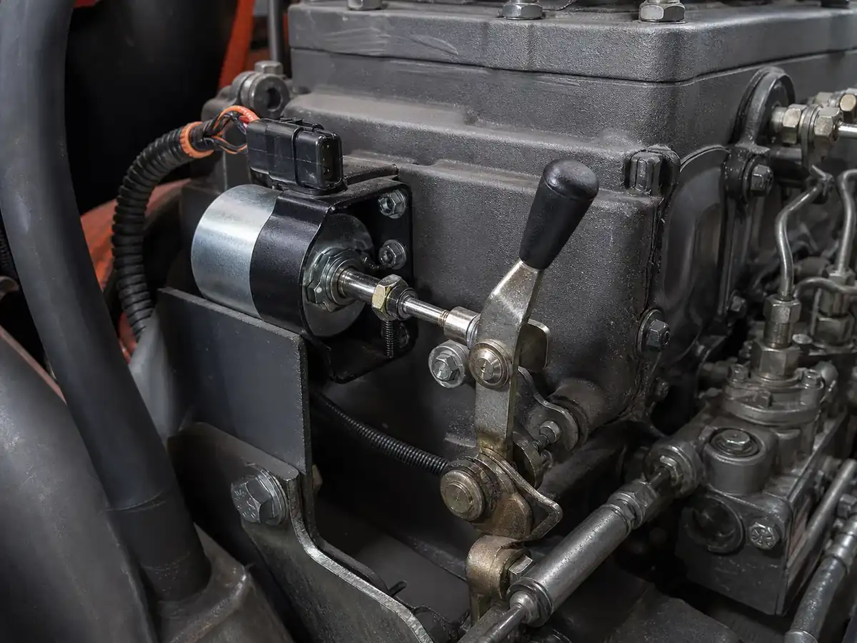 Diesel shutdown solenoid installed beside a fuel-control linkage on a heavy-duty engine