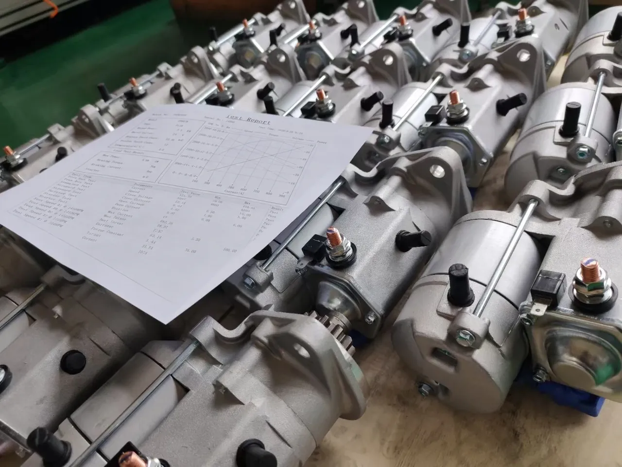 Starter motors on a workbench with a test-report sheet