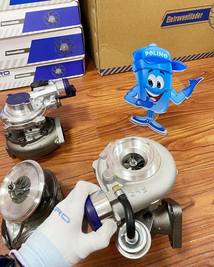 Gloved hand holding a complete turbocharger with its external connections visible