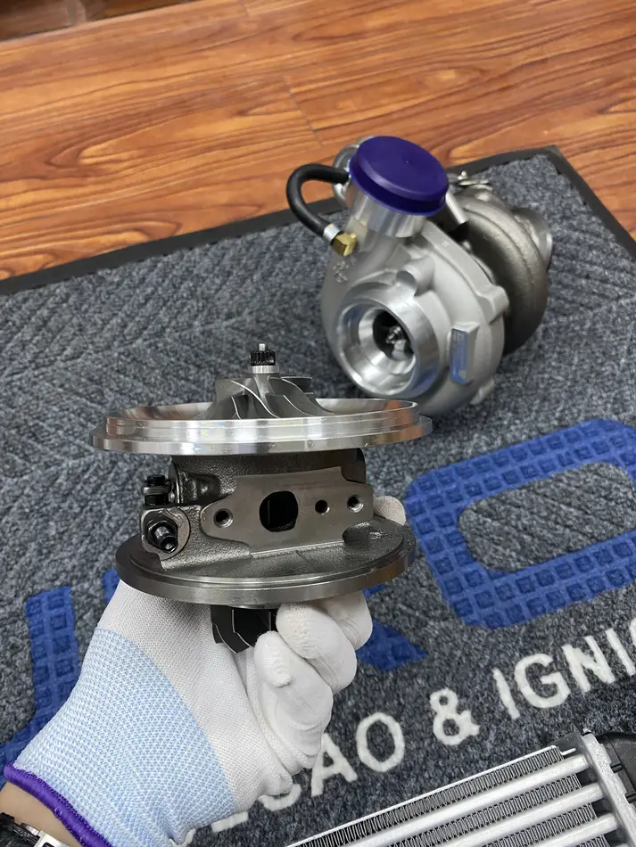 Real turbo center housing held in a glove with its oil-return face visible